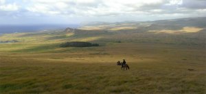 Horseback riders going down Poike, Rano Raraku volcano in background.